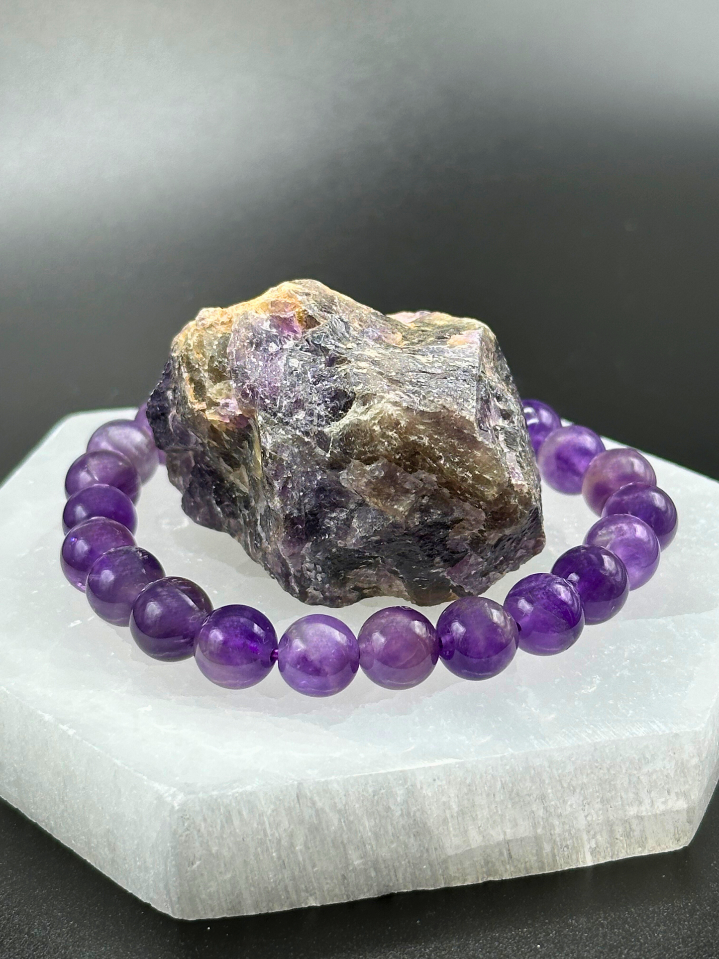 bracelet resting on top of quartz prop with amethyst stone in the middle 